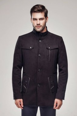 Yakışıklı Avrupalı model şık, koyu renk ceket giyiyor ve stüdyoda poz veriyor. 