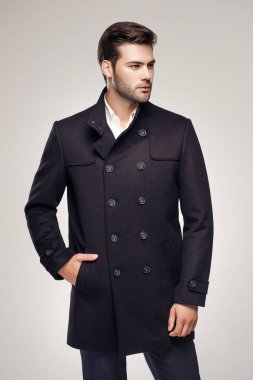 Yakışıklı Avrupalı model şık, koyu renk ceket giyiyor ve stüdyoda poz veriyor. 