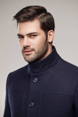 Yakışıklı Avrupalı model şık, koyu renk ceket giyiyor ve stüdyoda poz veriyor. 