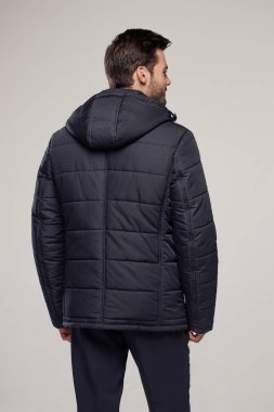 Sonbahar ya da kış mevsiminde havalı koyu renk ceket giyen bir adamın arka görüntüsü. Moda reklamcılığı için stüdyoda poz veren bir model.   