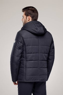 Sonbahar ya da kış mevsiminde havalı koyu renk ceket giyen bir adamın arka görüntüsü. Moda reklamcılığı için stüdyoda poz veren bir model.   