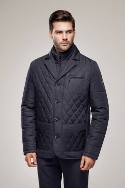 Yakışıklı, beyaz bir adam sonbahar ya da kış sezonu için koyu renk ceket giyiyor ve kamera önünde poz veriyor. Moda stüdyosu  