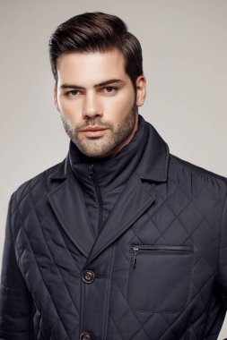 Yakışıklı, beyaz bir adam sonbahar ya da kış sezonu için koyu renk ceket giyiyor ve kamera önünde poz veriyor. Moda stüdyosu  