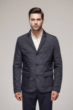 Yakışıklı, beyaz bir adam sonbahar ya da kış sezonu için koyu renk ceket giyiyor ve kamera önünde poz veriyor. Moda stüdyosu  