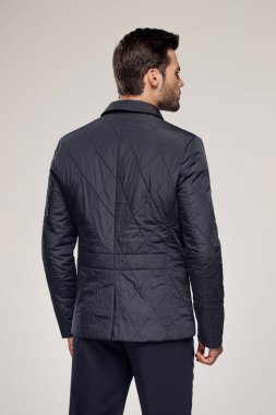 Sonbahar ya da kış mevsiminde havalı koyu renk ceket giyen bir adamın arka görüntüsü. Moda reklamcılığı için stüdyoda poz veren bir model.   