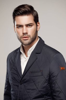 Yakışıklı, beyaz bir adam sonbahar ya da kış sezonu için koyu renk ceket giyiyor ve kamera önünde poz veriyor. Moda stüdyosu  