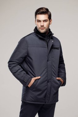 Yakışıklı, beyaz bir adam sonbahar ya da kış sezonu için koyu renk ceket giyiyor ve kamera önünde poz veriyor. Moda stüdyosu  