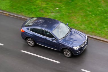 OSTRAVA, CZECHIA - 10 Ekim 2024: Mavi BMW X4 Coupe (F26) SUV arabası, hareket bulanıklığı etkisi