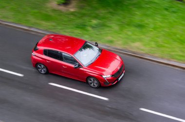 OSTRAVA, CZECHIA - 24 Nisan 2024: Kırmızı Peugeot 308 hatchback araba ıslak yolda hareket bulanıklığı etkisi