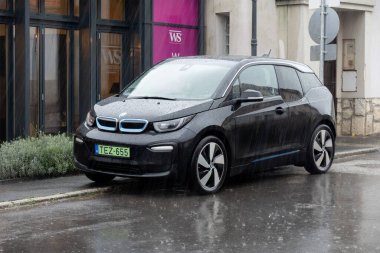 TOKAJ, HUNGARY - 27 Ekim 2023: Şiddetli yağmurda sokağa park edilmiş siyah BMW i3 elektrikli araba