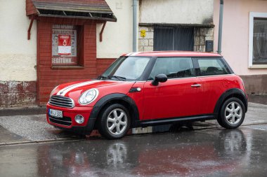 TOKAJ, HUNGARY - 27 EKİM 2023: Kırmızı Mini Cooper R56 aracı yağmur altında sokağa park edildi