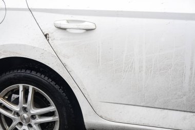 OSTRAVA, CZECHIA - 12 HAZİRAN 2024: alaşımlı tekerlekleri ve çamurlu kapı kolu olan çok kirli beyaz araba