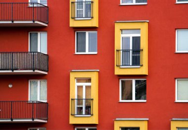 Sarı balkonlu modern daireler ve bir müteahhit tarafından yapılmış kırmızı duvarlar.