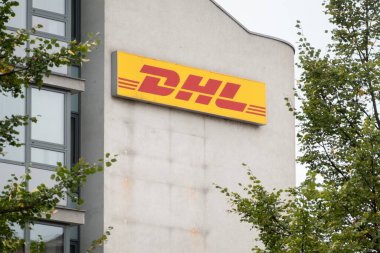 OSTRAVA, CZECHIA - 20 Ekim 2023: DHL şirketinin Sancaktarı ağaçların arkasındaki bina üzerine