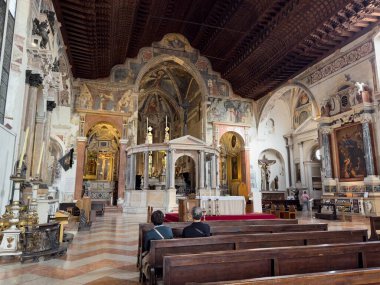 VERONA, İtalya - 28 Ekim 2024: San Fermo Maggiore Katedrali, sunakla iç mekan ve ziyaretçilerle banklar