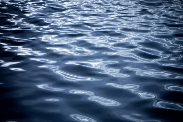 Sakin bir gecede mavi su dalgaları ve yansımaları