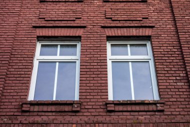 Zarar görmüş kırmızı tuğla duvarda iki pencere.