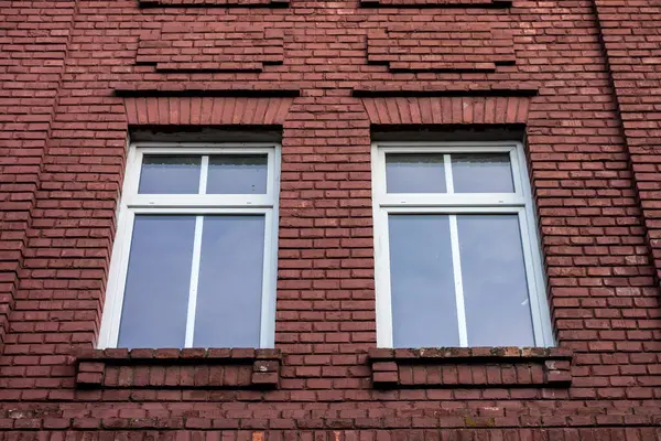 Zarar görmüş kırmızı tuğla duvarda iki pencere.