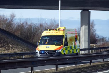 OSTRAVA, CZECHIA - 26 Ocak 2024: Çek Mercedes-Benz Sprinter ambulans aracı çarpışma bariyerinin arkasındaki otoyolda hareket bulanıklığı yarattı