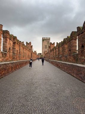 VERONA, ITALY - 28 Ekim 2024: Ponte di Castelvecchio turistlerle Verona 'daki kırmızı tuğla köprü, vetikal görüntü