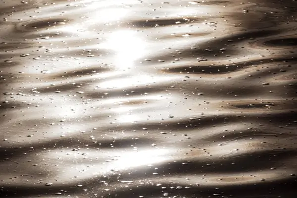 Kirlenmiş bir su yüzeyinde güneş yansıması