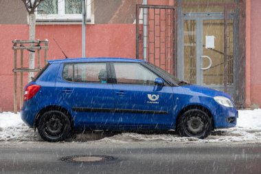 Ostrava, Çek Cumhuriyeti - 6 Aralık 2023: Ceska Posta Posta 'dan Blue Skoda Fabia II Kışın kar yağarken sokağa park etti