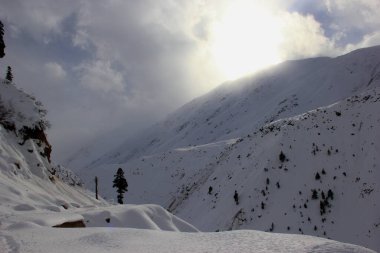 Kışın karla kaplı dağların ardında güneş batıyor.