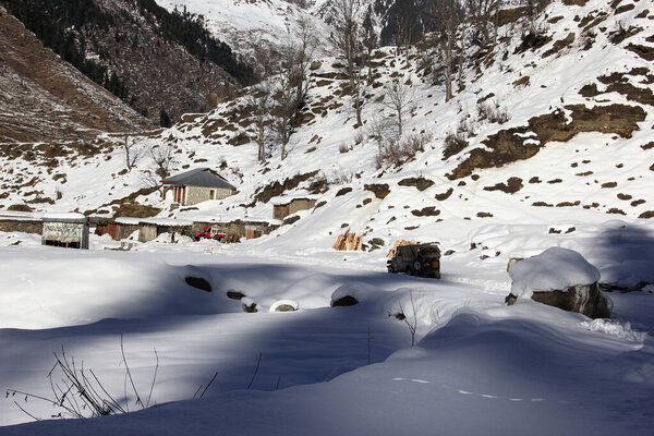 Джип, движущийся по заснеженным горам и заснеженным дорожкам в солнечный день