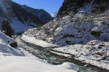 Güneşli bir günde, kar yağdıktan sonra buzul nehri olan bir dağ vadisi.