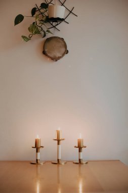 Hafif arka planda üç mum rahat bir atmosfer ve hoş altın bir ışık yaratır.