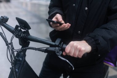 Bisikletli bir kuryedeki kurye telefonundaki haritaya bakar ve sipariş vermek için adres arar.