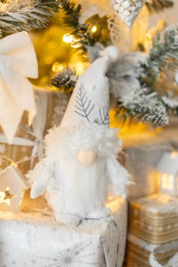 Kar altında beyaz cüce figürü beyaz süslemeli Noel ağacını kapladı. Beyaz, gümüş ve altın hediye kutuları. Yeni yıl, Noel. Ilık ışık. Yüksek kalite fotoğraf