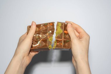 Famous Dubai chocolate with pistachio, tahini and kadaif broken in womans hands. Confectionery handmade sweets, chocolatier. High quality photo clipart