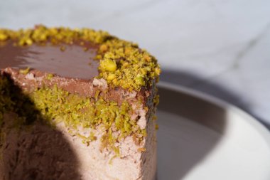 Dubai çikolatalı cheesecake 'i şam fıstığı ezmesi ve beyaz tabakta çikolata ganache ile kaplayın. Kopyalama alanı olan beyaz arkaplan. Hoşgörü, gurme tatlılar, aşçılık sanatı.