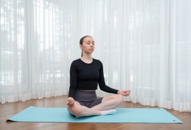 Yoga minderinde meditasyon yapan genç bir kadın. Egzersiz, esneme ve evde egzersiz. Farkındalık, rahatlama ve zihinsel refah kavramı. Yüksek kalite fotoğraf