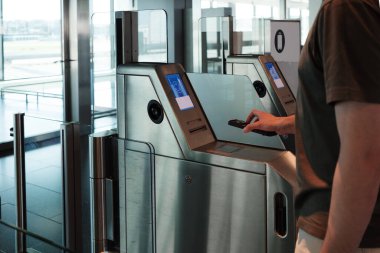 Yakın plan genç adam akıllı telefonunu otomatik havaalanı kapısında bir uçuş kartını taramak için kullanır. Dijitalleşme, kendini kontrol etme ve bağımsız seyahat kavramı. Yüksek kalite fotoğraf