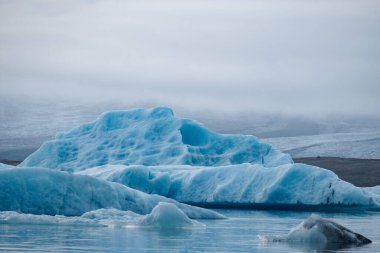İzlanda 'da bir buzul gölünde yüzen büyük mavi buzdağı. İklim, saflık, kutup doğası, kırılganlık, dinginlik ve çevresel farkındalık kavramı. Yüksek kalite fotoğraf