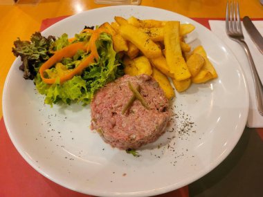 Bir restoranda biftek tartar ve patates kızartması.