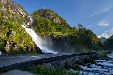 Latefossen, sarmal bir yolun kenarındaki kayalık uçurumlardan çarpıcı bir şelale akıyor. Bereketli bir yeşillik, güneşli bir günde huzurlu bir atmosfer yaratır..