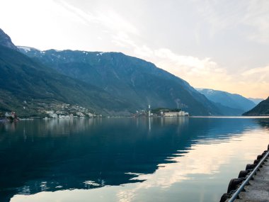 Odda 'nın merkezinden sakin bir Hardangerfjord' un nefes kesici manzarası alacakaranlıkta dağları ve gökyüzünü yansıtıyor.