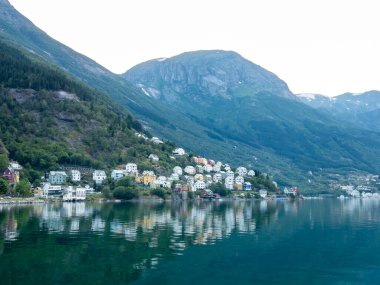 Odda, Norveç 'teki renkli evler sakin Hardangerfjord' u yansıtıyor. Etrafı yüksek dağlarla çevrili, alacakaranlıkta doğal güzellikleri sergiliyor..