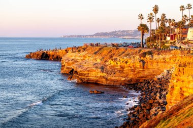 Günün son ışığı kayalık sahilde dans ediyor. Güneş yavaşça Sunset Cliffs, San Diego, CA 'da batıyor.