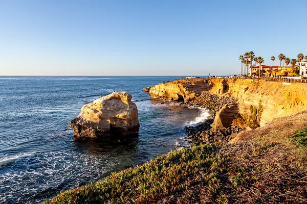 Dalgalar kayalıklara vuruyor, altın yansımaları, Sunset Cliffs, San Diego, CA 'nın yumuşak akşam ışığında parıldıyor..