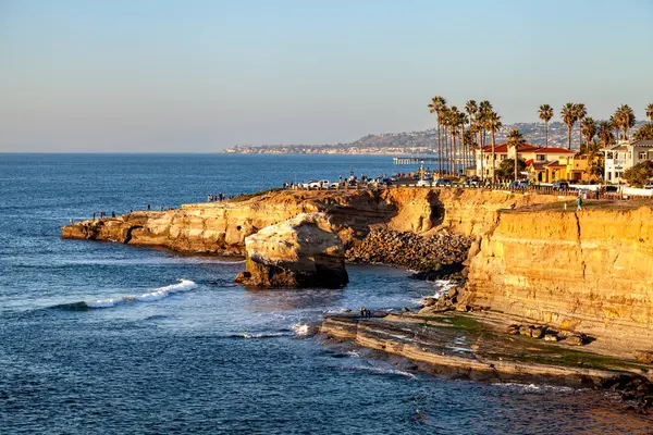 Sunset Cliffs 'in kumtaşı ve Ross kayalıkları altın ışıkla yıkanarak huzur dolu ve hayranlık uyandırıcı bir manzara yaratıyor.