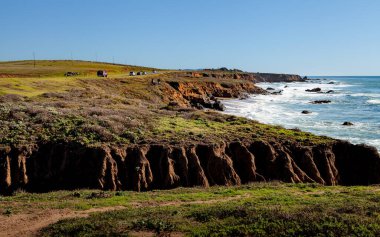 Kaliforniya, Kambriya 'daki engebeli kıyı şeridi kıyı şeridi boyunca uzanır. Dalgalar Pasifik Sahil Otobanı' nın yanındaki kayalara hafifçe çarpar.