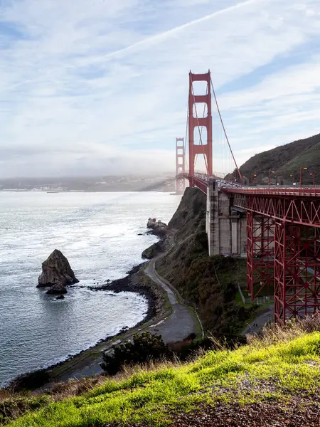 Golden Gate Köprüsü, körfez boyunca kayalık kıyı şeritleriyle çevrili görkemli bir şekilde uzanır. Mavi gökyüzü çarpıcı manzarayı güzelleştiriyor, turistleri ve yerlileri davet ediyor.