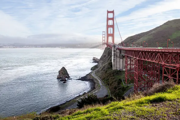 Golden Gate Köprüsü 'nün ışıldayan sulara uzanan nefes kesici manzarası. Yeşil tepeler San Francisco 'nun manzarasını güzelleştirirken Rocky oluşumları kıyı şeridi boyunca uzanır..