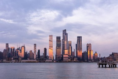 Weehawken, NJ, ABD 19 Nisan 2025: Günbatımında Manhattan Hudson Yards 'ın cam gökdelenlere çarpıcı yansımaları. Hudson Nehri 'nin karşısından yakalandı..