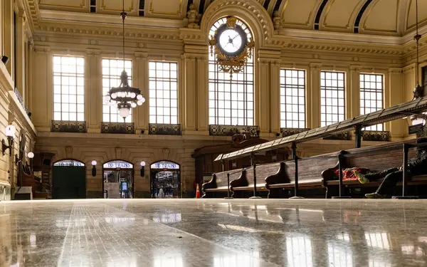 Hoboken, NJ, ABD - 19 Mayıs 2025: Öğleden sonra ışığı Hoboken Terminalinde ahşap banklar ve üzerinde büyük bir vintage saat ile cilalı zeminlere yansıyor.