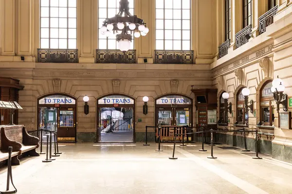 Hoboken, NJ, ABD - 19 Mayıs 2025: Hoboken Terminalinde büyük avizeler ve yüksek kemerli pencereler altında tren rayları görmek.